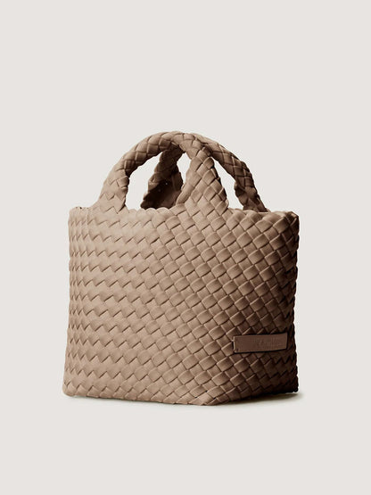 Naghedi St. Barths Petit Tote in Cashmere: a taupe handwoven neoprene mini tote bag with two top handles and a small rectangular logo patch on the side.