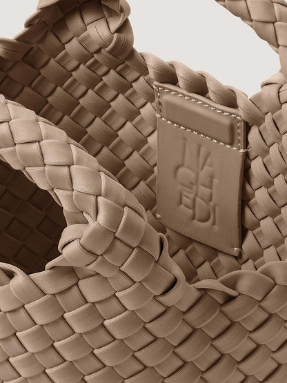 Close-up of a taupe handwoven neoprene Naghedi St. Barths Petit Tote in Cashmere with an interior branded leather patch.