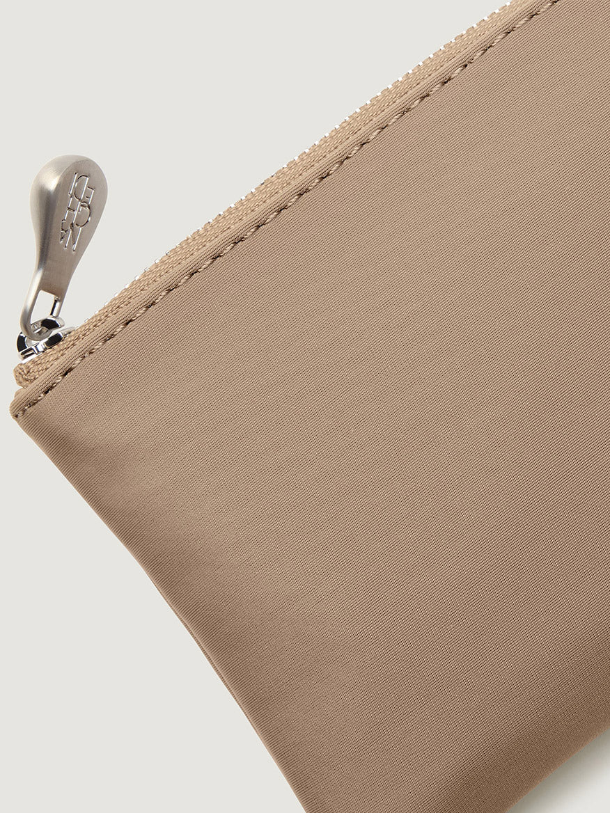 Naghedi St. Barths Petit Tote in Cashmere, a beige zippered mini bag with a metallic pull tab.