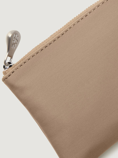 Naghedi St. Barths Petit Tote in Cashmere, a beige zippered mini bag with a metallic pull tab.