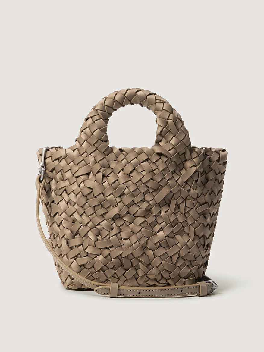 Naghedi St. Barths Petit Tote Nest Weave in Cashmere, a small taupe bag made of woven material with braided top handles and a thin adjustable shoulder strap.