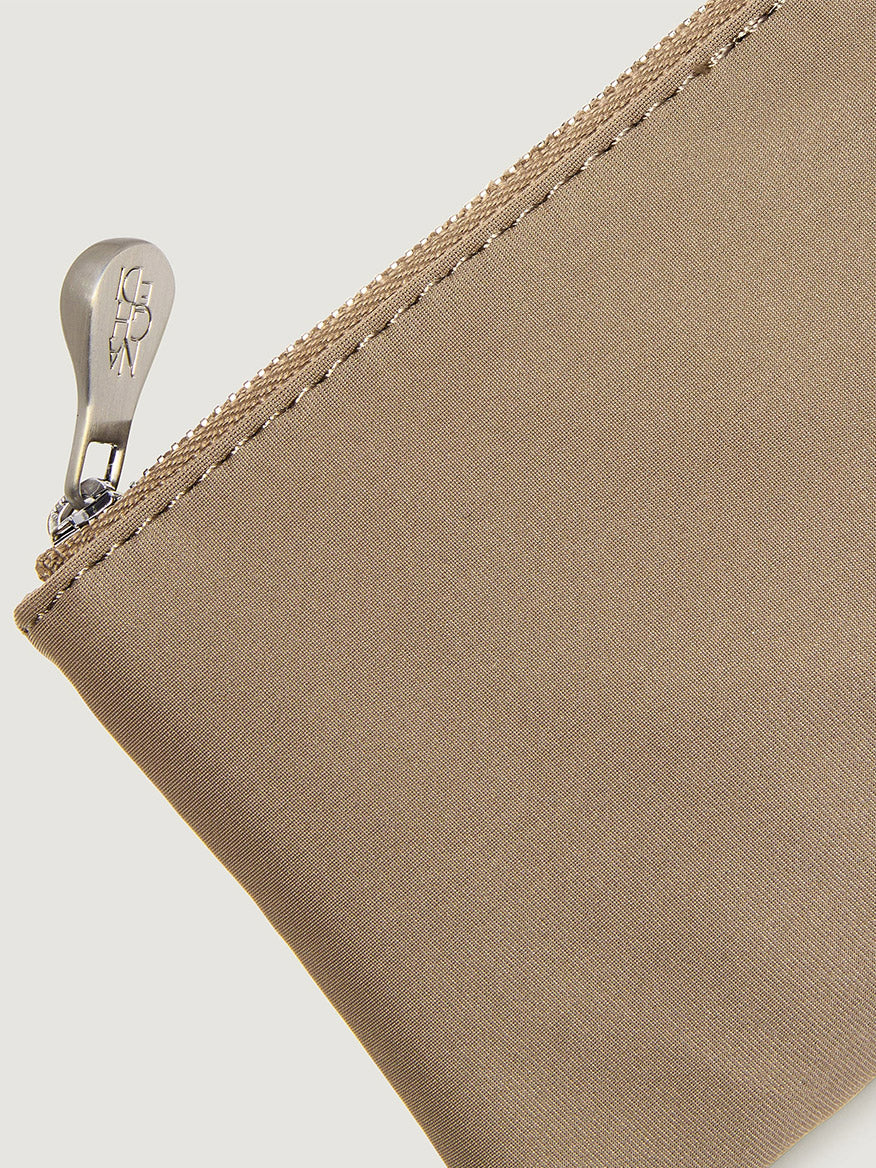 Close-up of a tan Naghedi St. Barths Petit Tote Nest Weave in Cashmere zippered pouch with a metallic pull.
