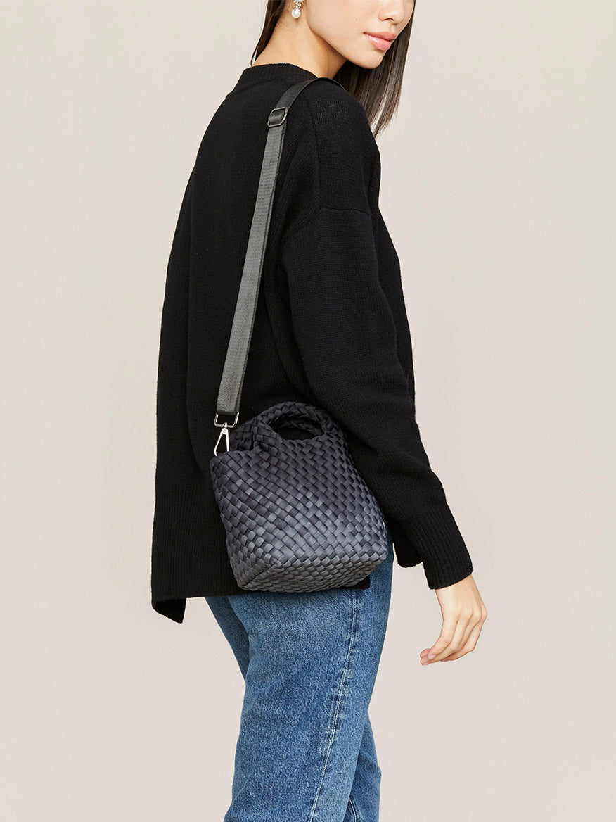 Woman in a black sweater and jeans carrying a Naghedi St. Barths Petit Tote in Graphic Ombre Basalt.