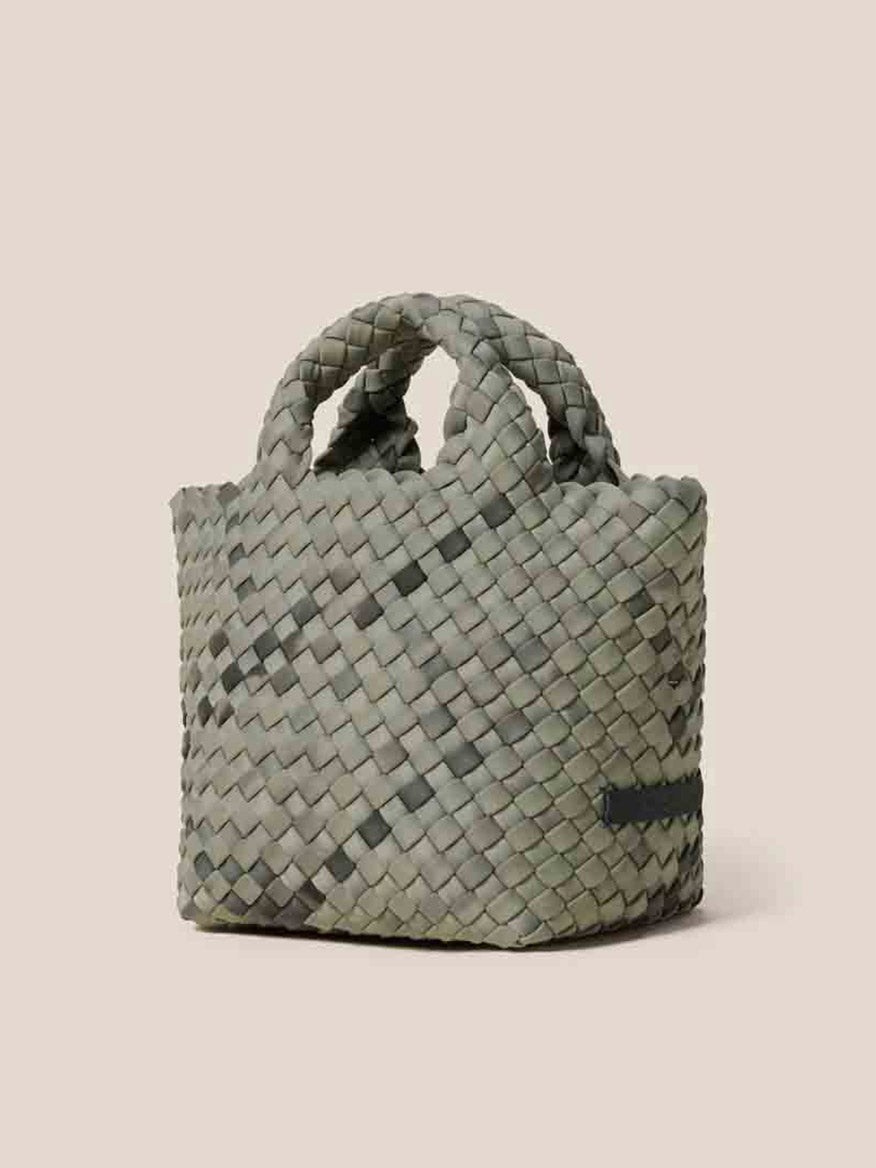 The Naghedi St. Barths Petit Tote in Watercolor Neptune is a small woven basket with handles, crafted from handwoven neoprene in a chic gray-green hue, elegantly set against a plain beige background.