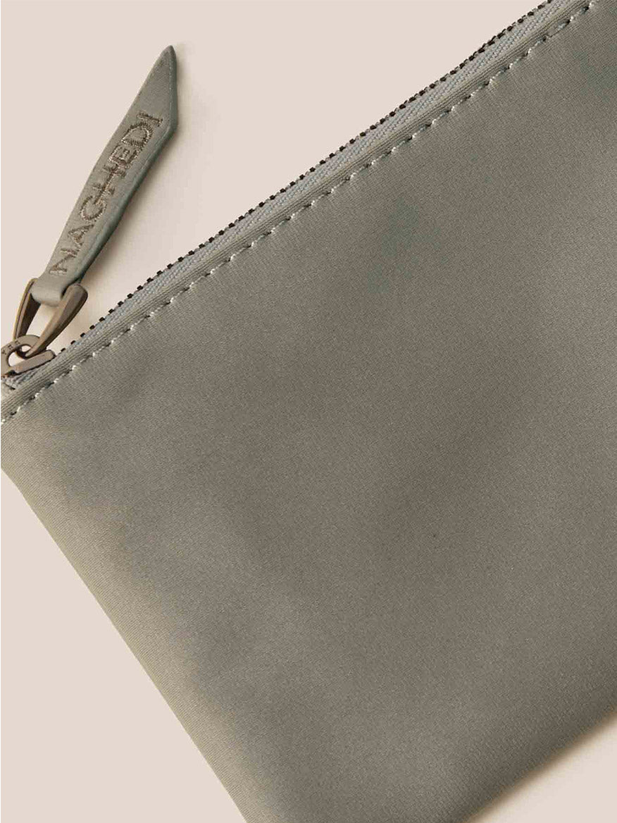 A zippered gray pouch with a textured surface, showcasing the brand name on the zipper pull, complements your Naghedi St. Barths Petit Tote in Watercolor Neptune beautifully.