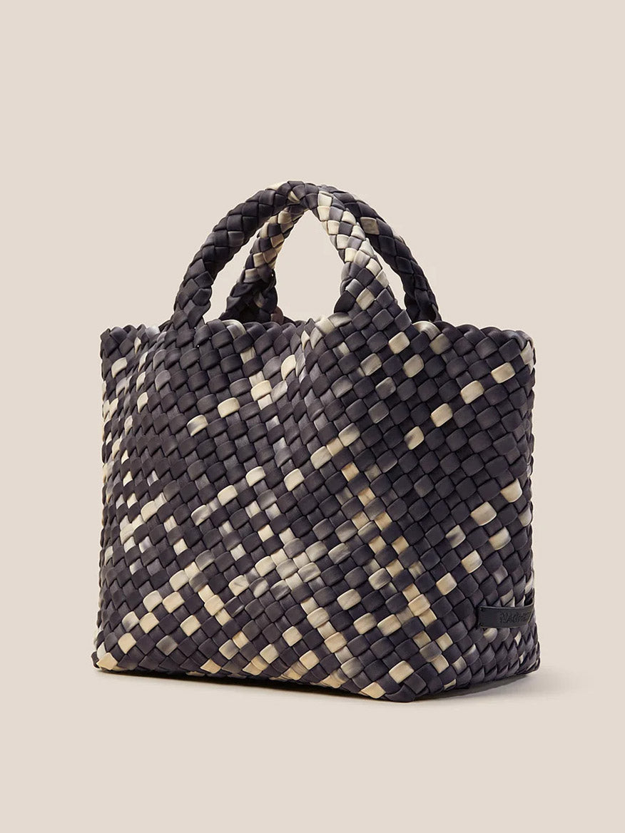 The Naghedi St. Barths Small Tote in Watercolor Nimbus is a handwoven neoprene handbag showcasing a checkered black and beige pattern with two sturdy handles against a plain background. This chic accessory includes a detachable crossbody strap for versatile wear.