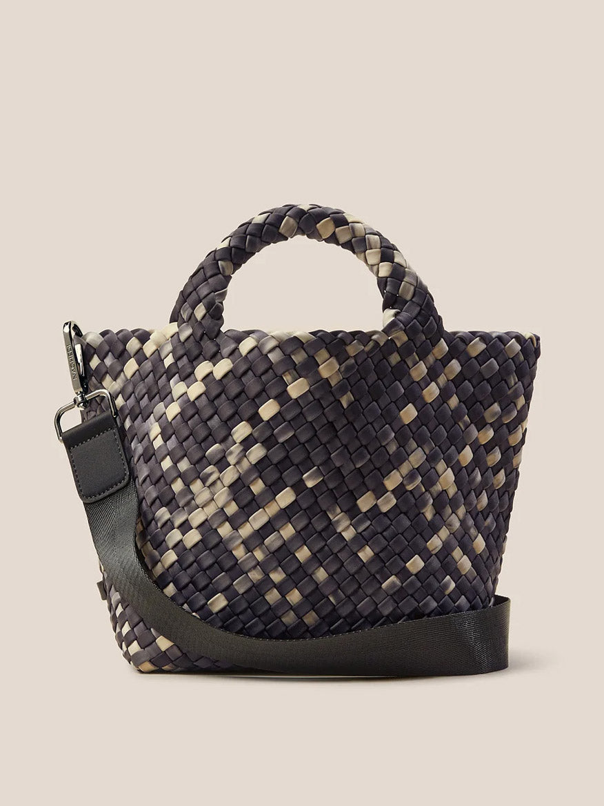 The Naghedi St. Barths Small Tote in Watercolor Nimbus is a woven handbag with a checkered pattern in dark gray and beige. It features a short handle, a detachable crossbody strap, and is crafted from handwoven neoprene, making it perfect for versatile style on the go.
