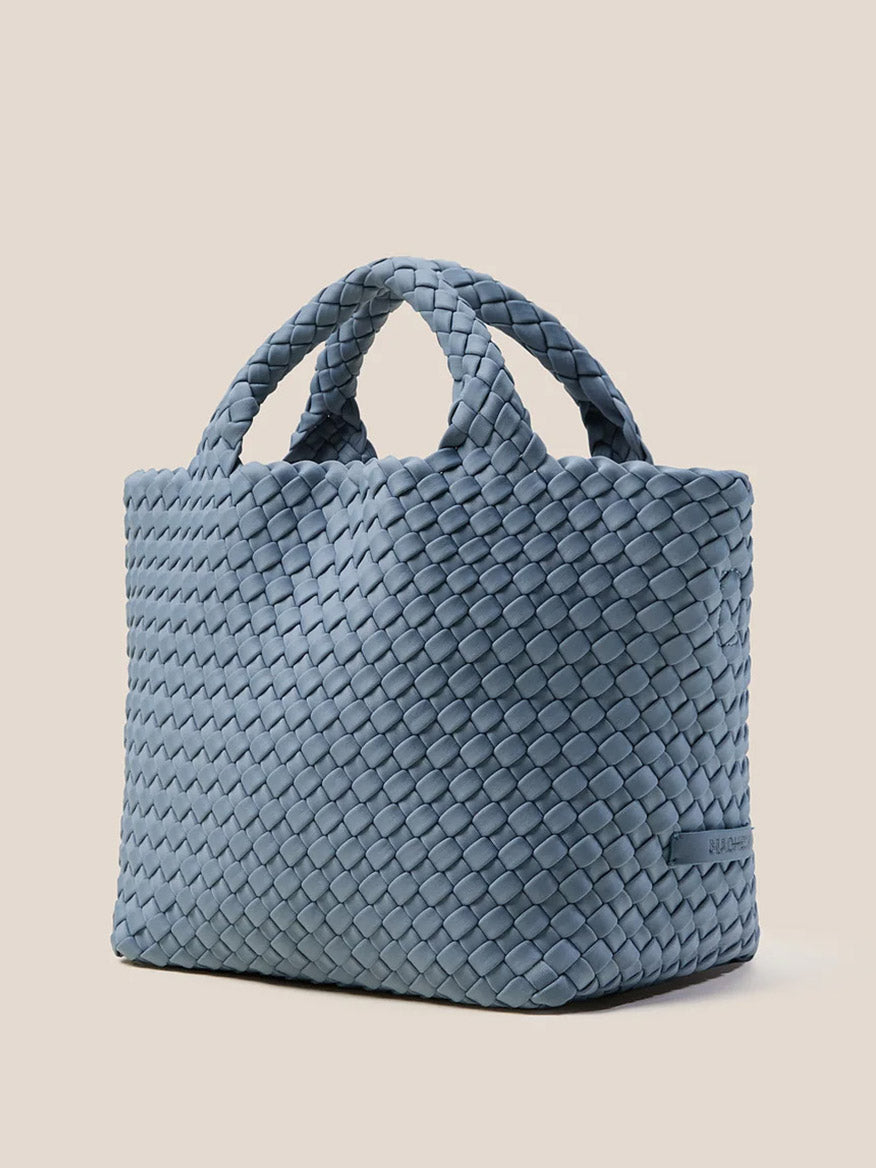 The Naghedi St. Barths Small Tote in Solid Nova, handwoven from neoprene with short handles, rests elegantly on a neutral background.