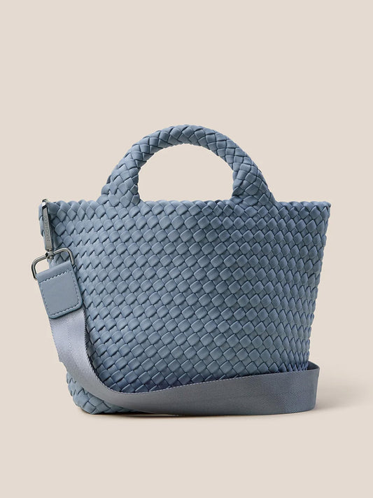 The Naghedi St. Barths Small Tote in Solid Nova is a blue handwoven neoprene bag with short handles and an adjustable crossbody strap, set against a plain background.