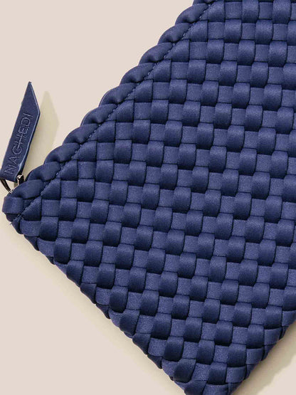 Close-up of a blue handwoven neoprene fabric pouch with a zipper pull featuring the brand name "Naghedi St. Barths Small Tote in Solid Ink Blue." The design is compact yet stylish, making it perfect to pair with a crossbody strap for easy carrying.