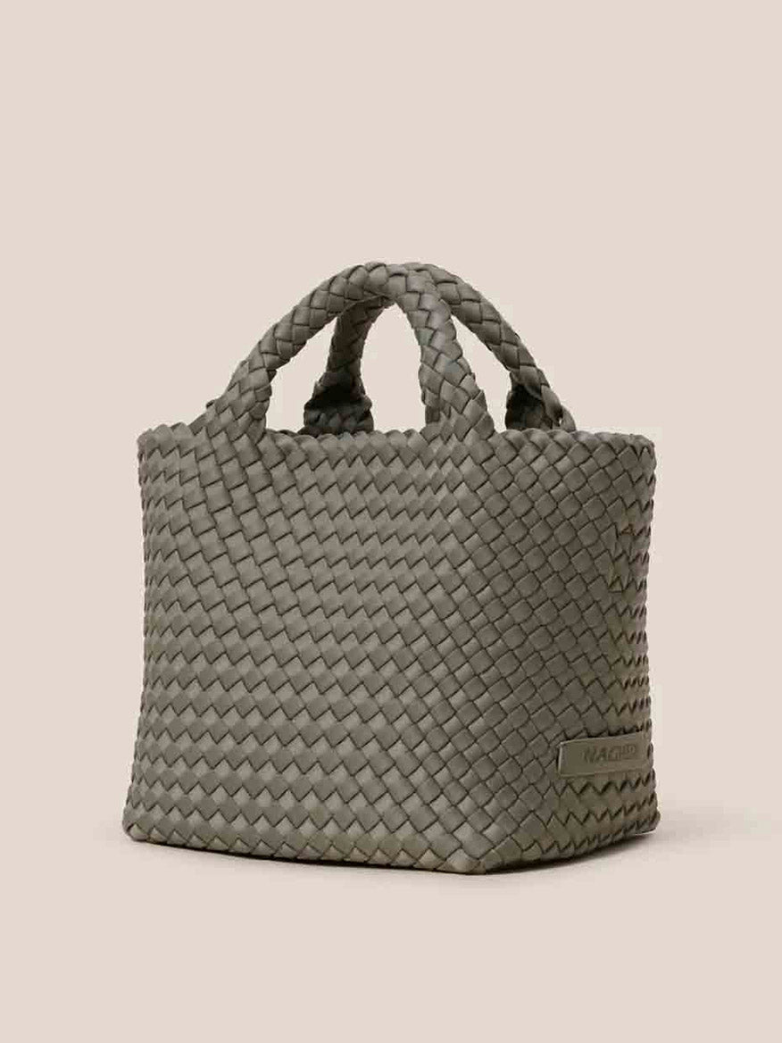 The Naghedi St. Barths Small Tote in Solid Laurel is a handwoven neoprene bag in an elegant gray, boasting two durable handles set against a light backdrop.