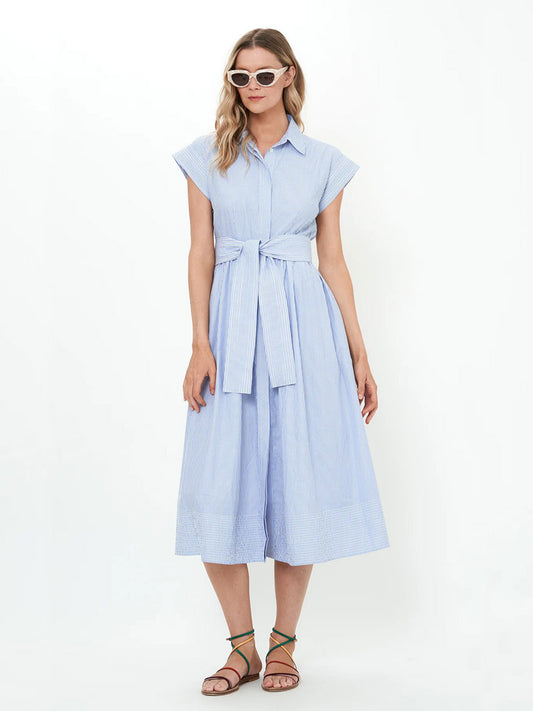 A person wearing the Oliphant Belted Shirt Dress in Chatham Blue, sunglasses, and sandals stands against a plain background.