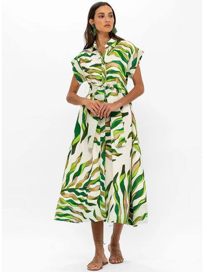 Woman posing in an Oliphant Belted Shirt Dress in Maldive Green with green abstract patterns, featuring a cinched waist and midi length.