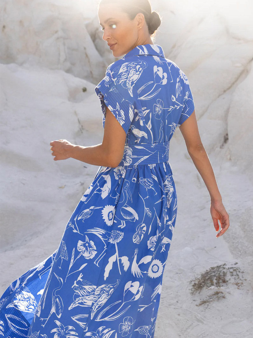 Woman wearing an Oliphant Belted Shirt Dress in Audubon Blue with double stitch detailing, looking back over her shoulder outdoors.