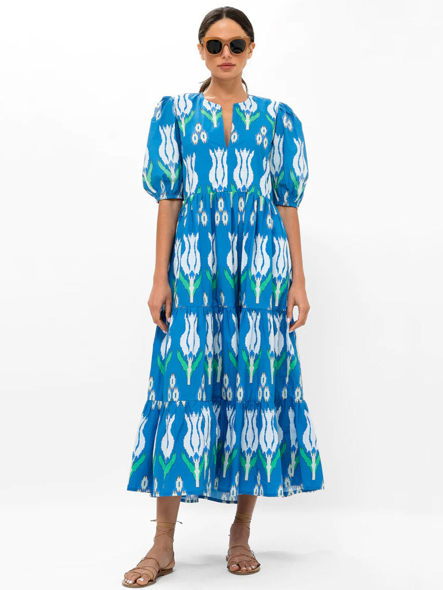Woman in an Oliphant Puff Sleeve Maxi Dress in Sumba Blue Tulip with sunglasses and pockets standing against a white background.