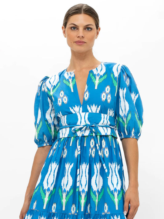 Woman in a Oliphant Tokyo Belt in Sumba Blue Tulips floral puff sleeve maxi dress, made of cotton poplin, standing against a white background.