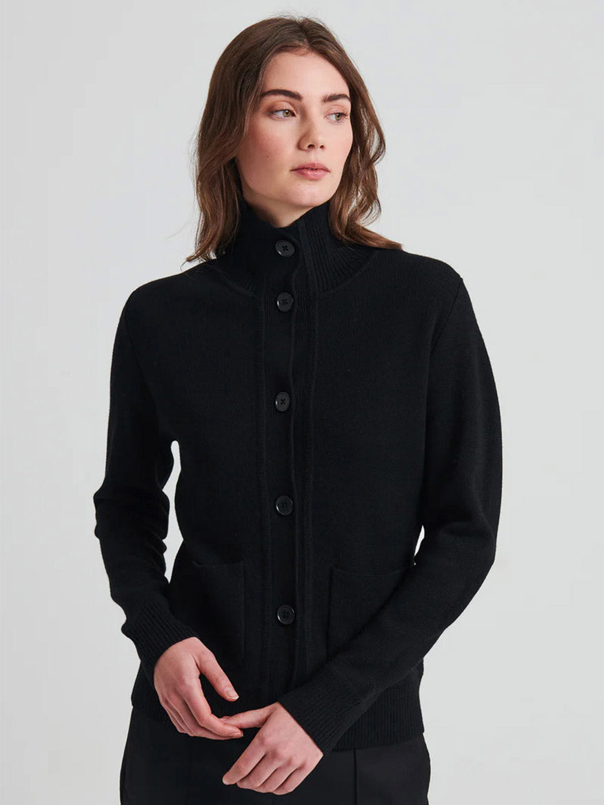 A woman in a black sweater, effortlessly styled with the Patrick Assaraf Merino Button Front Milano Jacket in Black, exudes sophistication.