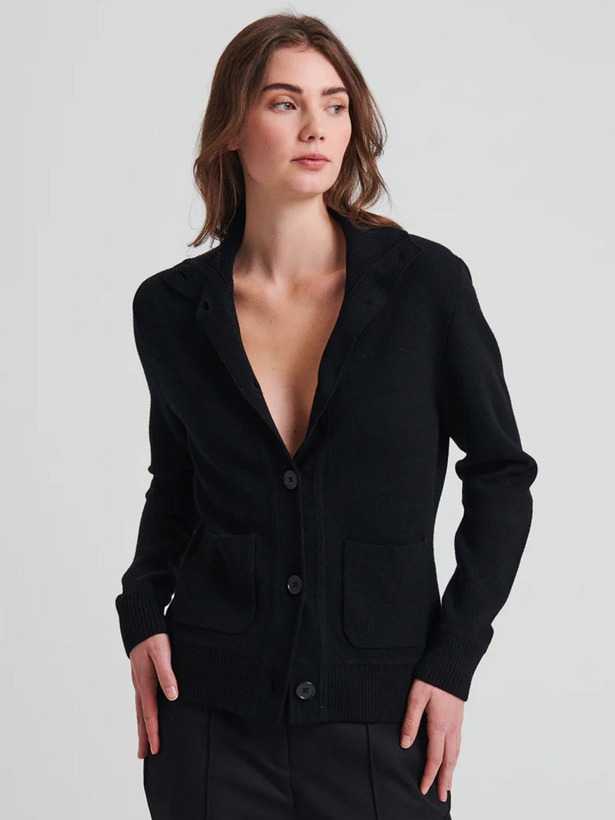 Standing against a plain background, a person wears the Patrick Assaraf Merino Button Front Milano Jacket in black, ideal for layering over a low-cut top.