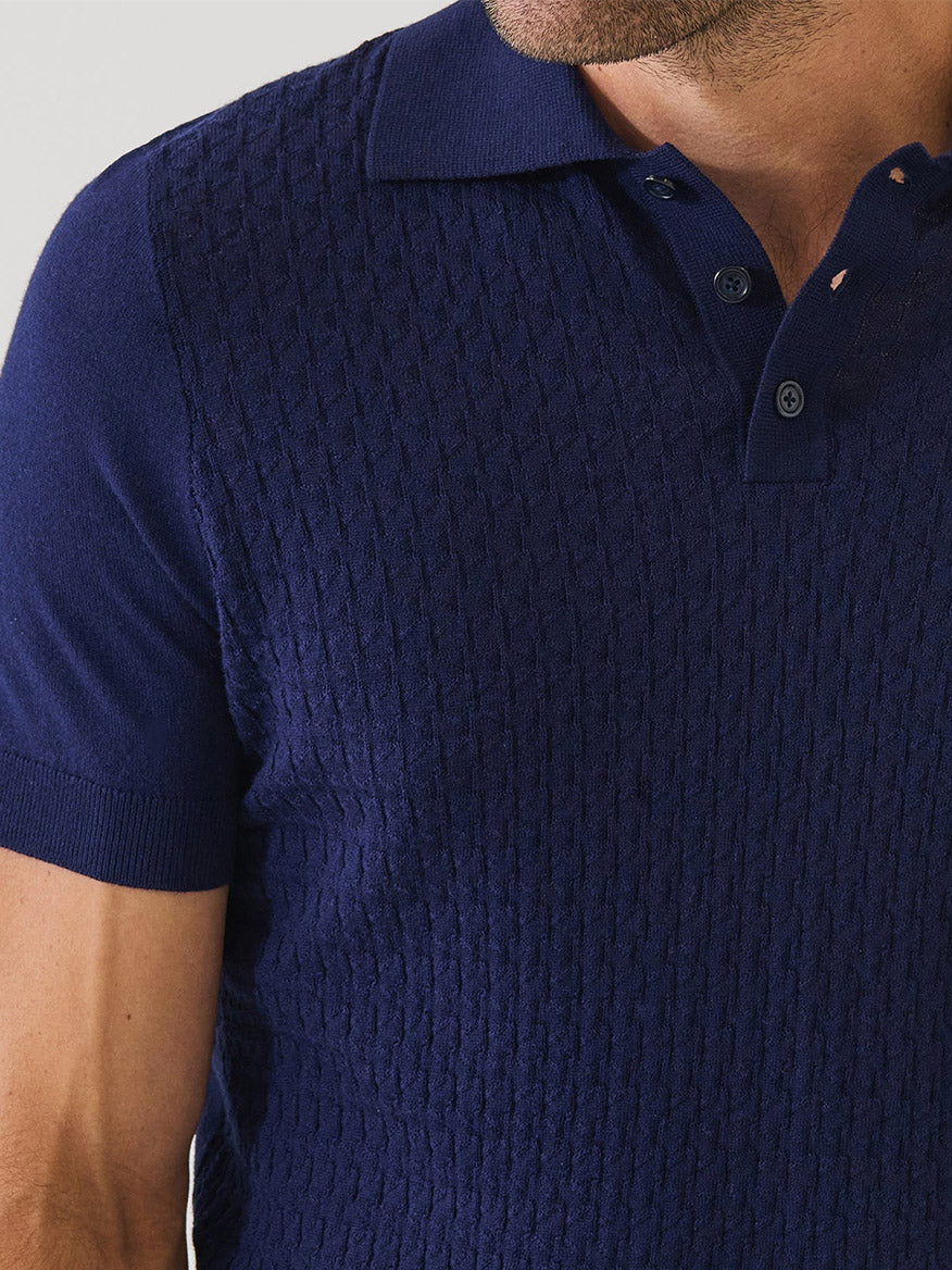 A close-up of a man wearing the Patrick Assaraf Cotton Blend Triangle Stitch Polo in Navy, a lightweight short sleeve knit with a textured triangle stitch pattern and buttoned collar.