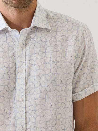 Man wearing the Patrick Assaraf Geometric Print Linen Shirt in Lake, a short sleeve pure linen shirt with a subtle blue geometric circle pattern, shown from shoulders to mid-arm.