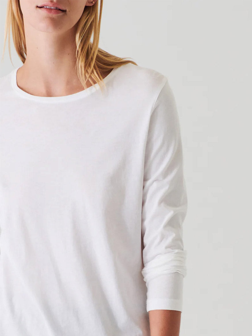 A person wearing a Patrick Assaraf Lightweight Pima Cotton T-Shirt in white stands against a neutral background.