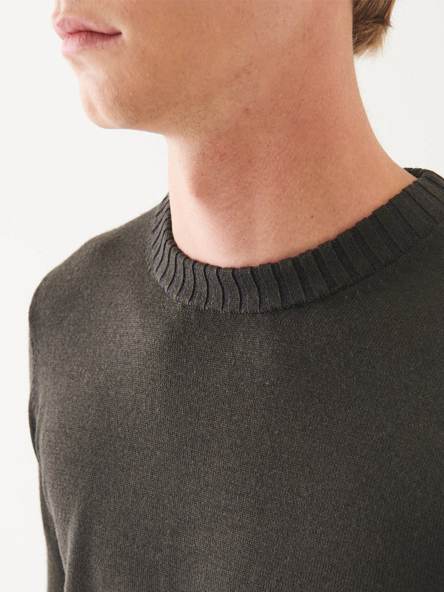 Close-up of a person wearing the Patrick Assaraf Plaited Merino Wool Crewneck in Dark Brown, showcasing its finely crafted design. The focus is on the neck and upper chest area, accentuating the sleek silhouette.