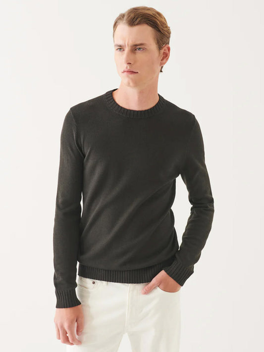 A person wearing the sleek Patrick Assaraf Plaited Merino Wool Crewneck in Dark Brown and white pants stands against a plain background.