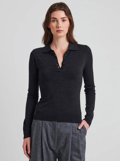 A woman in a Superfine Merino Fitted Polo in Coal Melange by Patrick Assaraf cuts a slim silhouette, exuding elegance with its soft merino stretch yarn.