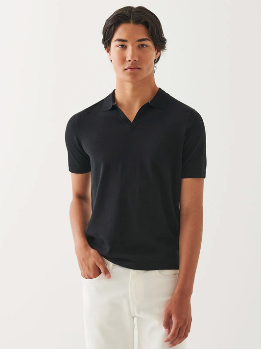 A person stands facing forward in the Patrick Assaraf Cotton Cupro Open Polo in Black and white pants against a plain light background, highlighting the polo's versatile style.