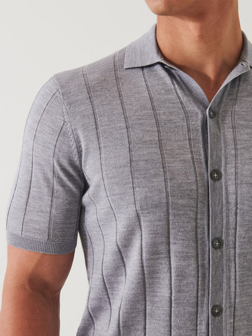 Close-up of a man wearing a Patrick Assaraf Merino Wool-Silk Blend Knit Button Up in Ghost with vertical stripes and button details, focusing on the shirt and upper torso.