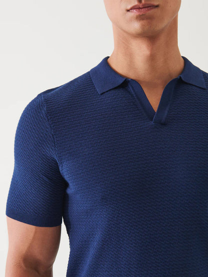 Close-up of a man wearing a Patrick Assaraf Cotton Cupro Open Polo in Navy, focusing on the shirt's texture and collar, with the man's face partially visible.
