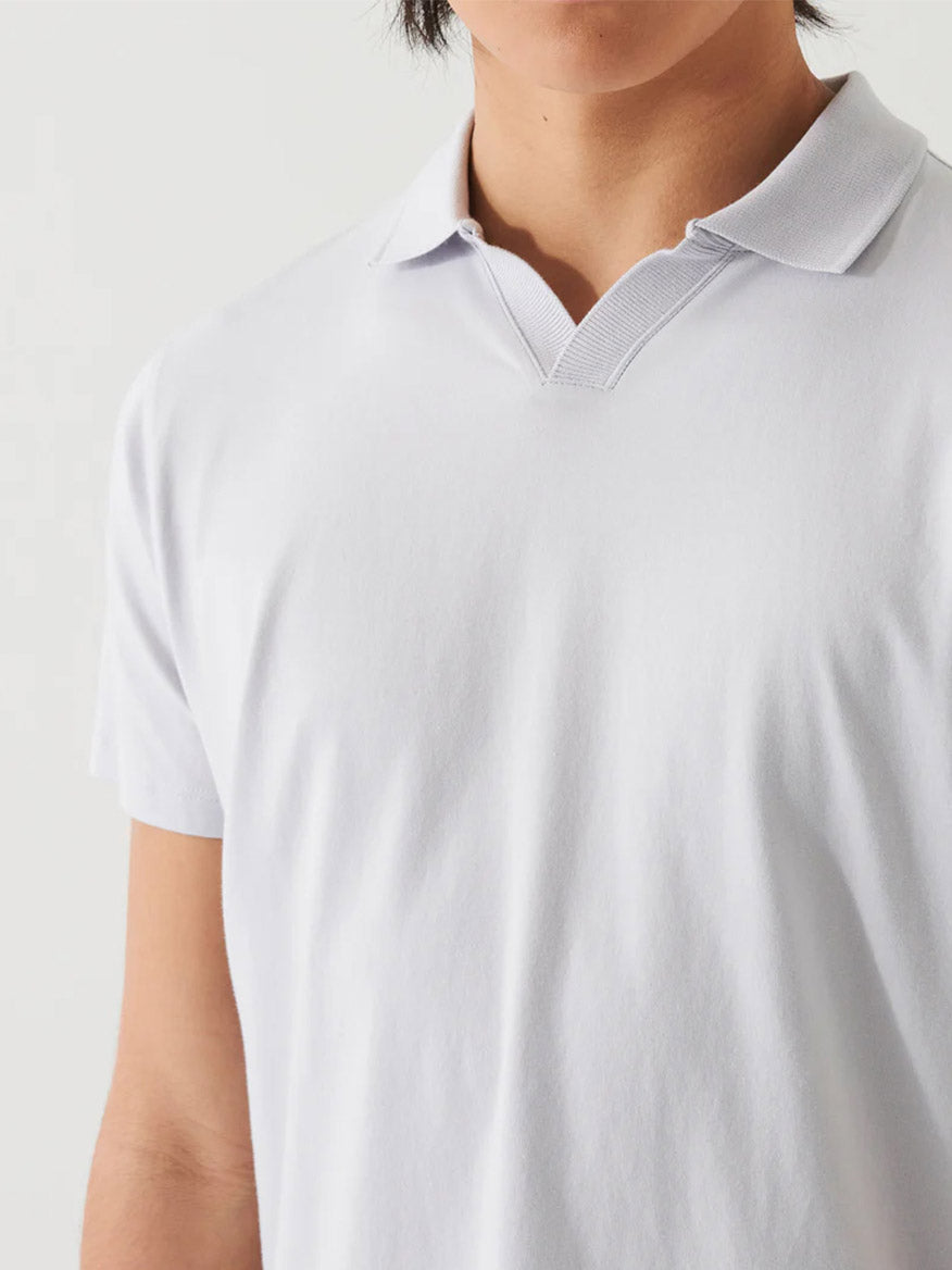 Close-up of a person wearing a Patrick Assaraf Pima Cotton Stretch Open Polo in Glacier, with a focus on the collar and upper chest area.