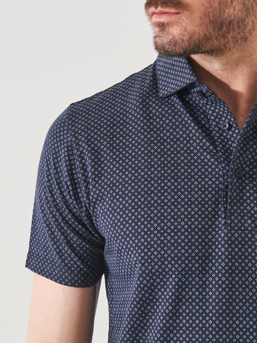 Close-up of a man wearing a Patrick Assaraf Pima Cotton Stretch Printed Polo in Midnight Mini Floral Geo, focusing on the shirt collar and top buttons, with his face not visible.