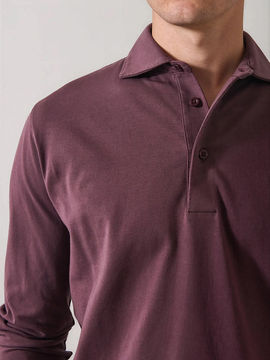 A man wearing the Patrick Assaraf Pima Cotton Stretch Long Sleeve Polo in Prune, featuring a collar and two-button placket, stands against a plain light background with his face partially out of frame.