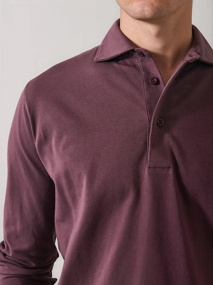 A man wearing the Patrick Assaraf Pima Cotton Stretch Long Sleeve Polo in Prune, featuring a collar and two-button placket, stands against a plain light background with his face partially out of frame.