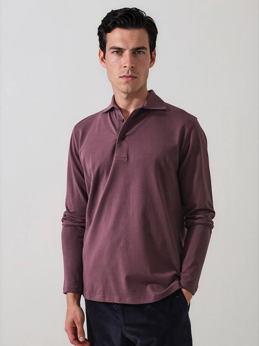 A man wearing the Patrick Assaraf Pima Cotton Stretch Long Sleeve Polo in Prune and dark pants stands against a plain light background with a neutral expression.