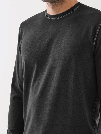 A man wearing the Patrick Assaraf Pima Cotton Stretch Vintage Wash Long Sleeve T-Shirt in Black, shown from the shoulders to mid-torso, stands against a plain light background.
