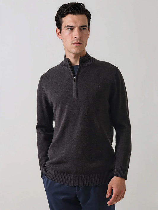 A man wearing the Patrick Assaraf Merino Plaited Quarter Zip in Brownie and navy pants stands against a plain light background, looking to the side with a neutral expression. The refined silhouette of the sweater offers lightweight warmth, seamlessly blending comfort with contemporary style.