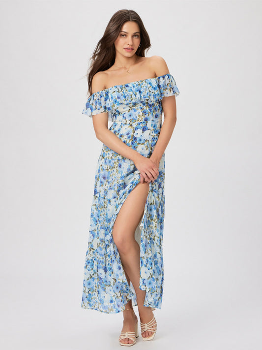 Woman wearing an off-the-shoulder floral Paige Carmelia Dress in French Blue Multi and white heeled sandals, standing in a studio with a plain background.