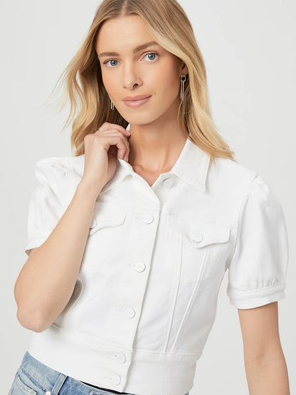 A person with long blonde hair wearing a short-sleeve white shirt and the Paige Kendra Jacket in Crisp White poses against a plain background.