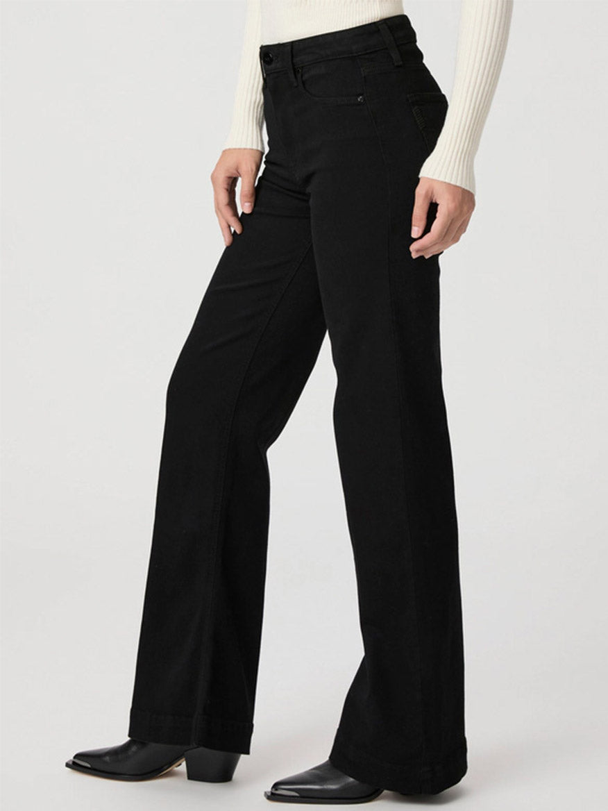 Person wearing Paige Leenah 32" Wide Leg Jeans in Black Shadow, a white ribbed sweater, and black ankle boots.