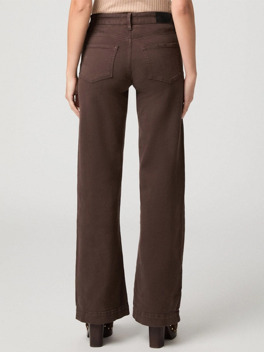 A person is wearing the Paige Leenah 32″ Wide Leg Jean in Rich Chocolate with a beige top, standing with their back to the camera against a plain light background.