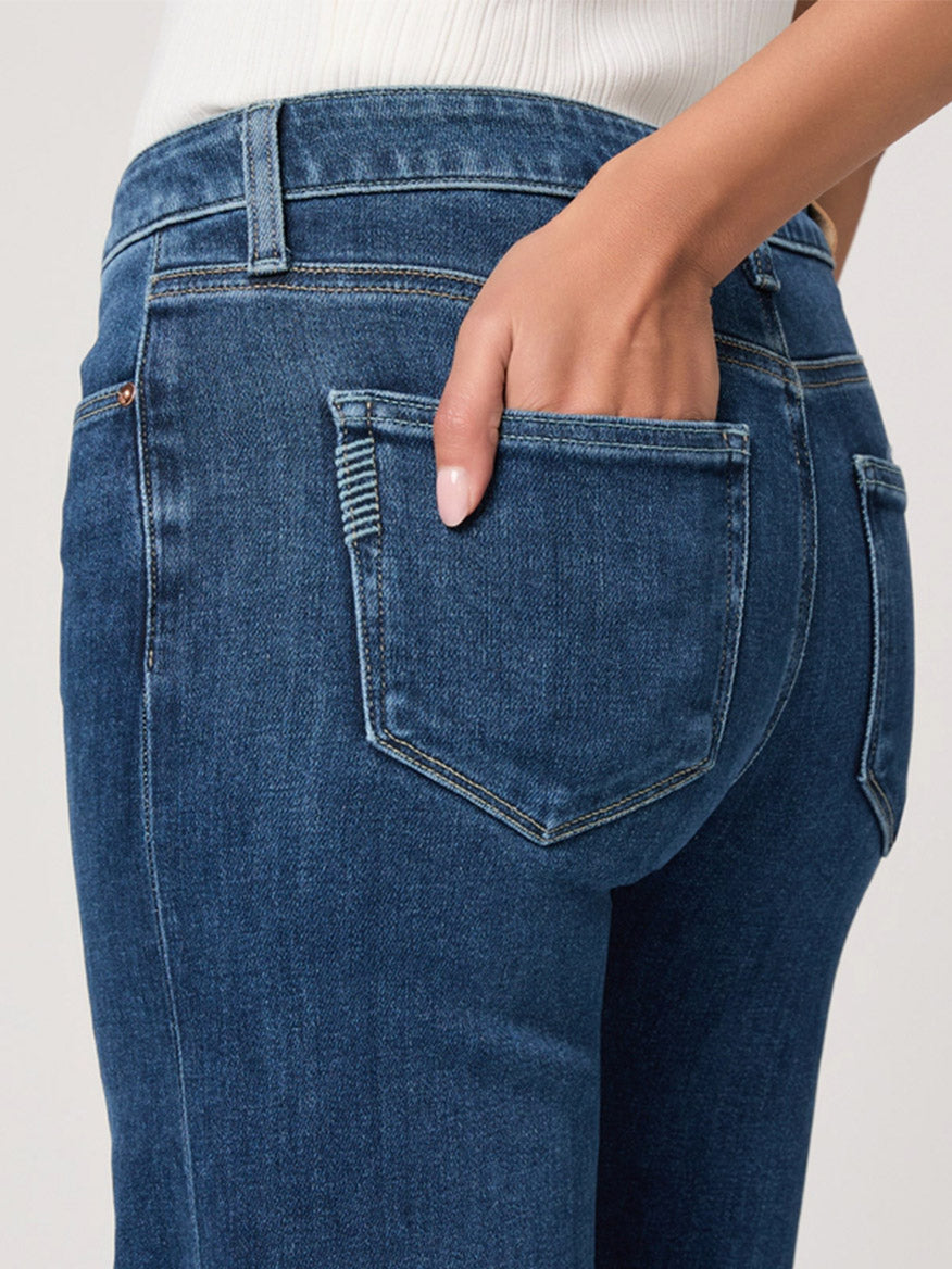 A person wearing the Paige Leenah 32" Wide Leg Jean in Venetian Breeze places their right hand in the back pocket, with a plain background highlighting the jeans and hand.