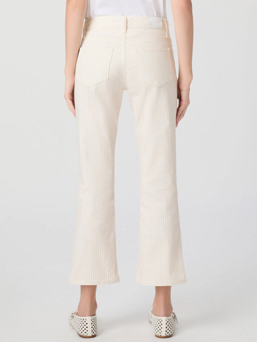 Person wearing Paige Mason Crop Bootcut Jean in Tonal Stripe, paired with a white top and white perforated shoes, shown from the back against a plain background.