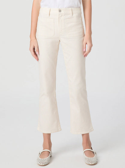 Wearing Paige Mason Crop Bootcut Jean in Tonal Stripe, a white shirt, and white cutout flat shoes, the person stands against a plain light background.