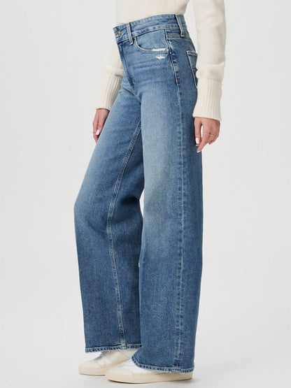 A person wearing a cream sweater and Paige Sasha 32" Wide Leg Jean in Storybook Distressed stands against a plain background.