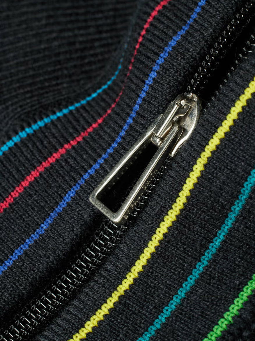 Close-up of the Paul Smith Merino Wool Sports Stripe Half Zip in Black, featuring a metallic zipper and black fabric with blue, red, yellow, and green diagonal stripes.
