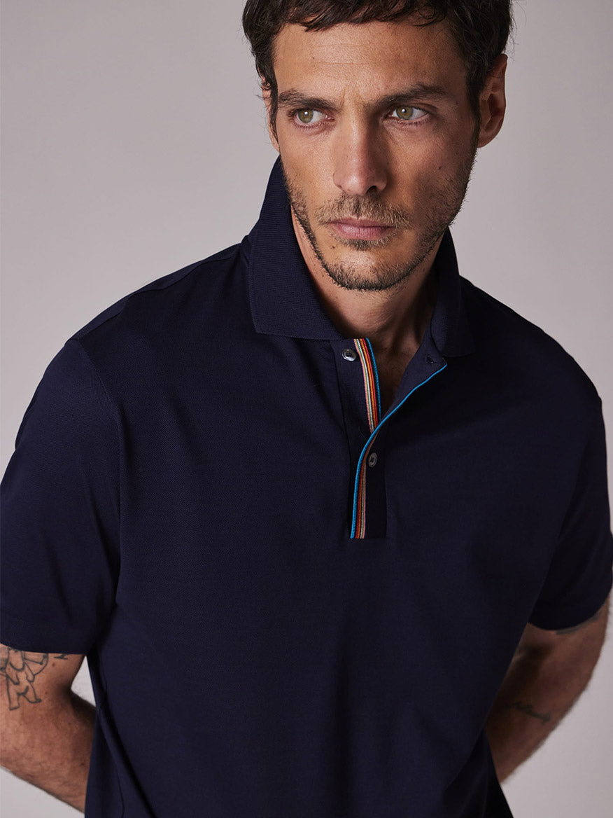 A man with short brown hair and light facial hair wears the Paul Smith Signature Stripe Trim Polo Shirt in Dark Navy, looking slightly to his left against a plain background.