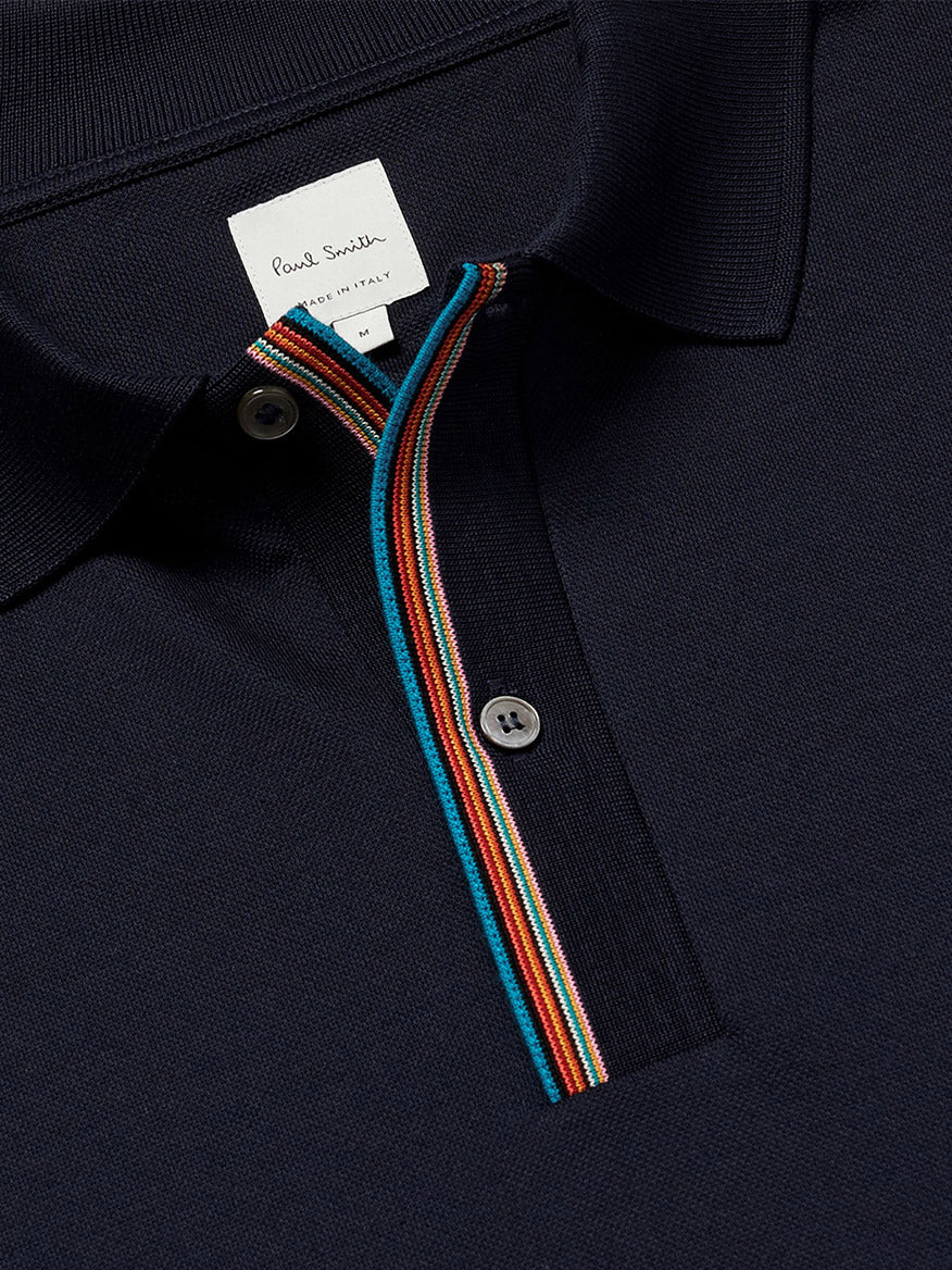 Close-up of the Paul Smith Signature Stripe Trim Polo Shirt in Dark Navy, crafted from cotton pique, featuring a Signature Stripe trim on the button placket and a visible Paul Smith label on the collar.