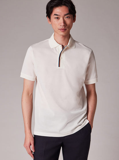 A person stands facing forward, wearing the Paul Smith Signature Stripe Trim Polo Shirt in White with dark pants, set against a plain background.